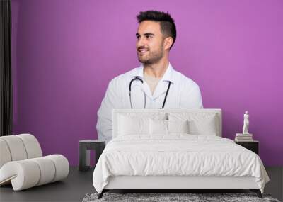 Young man wearing a doctor gown and with arms crossed looking side Wall mural