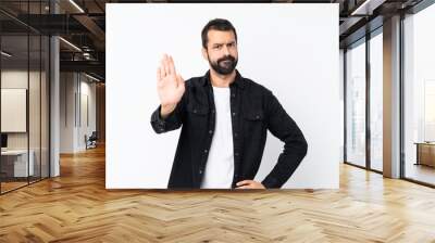 Young man with beard over isolated white background making stop gesture Wall mural