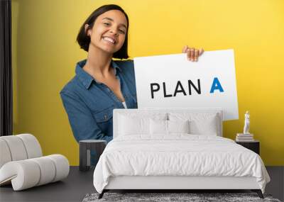 Young mixed race woman isolated on yellow background holding a placard with the message PLAN A with happy expression Wall mural