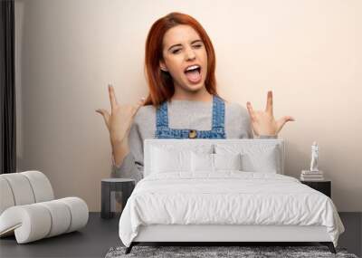 Young redhead woman over isolated background making rock gesture Wall mural