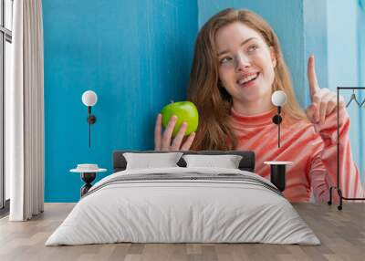 Young redhead woman with an apple at outdoors intending to realizes the solution while lifting a finger up Wall mural