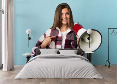 Young Slovak woman isolated on blue background holding a megaphone and with surprise facial expression Wall mural