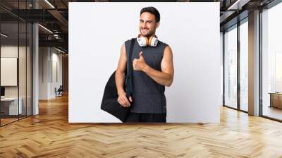 Young sport man with sport bag isolated on white background giving a thumbs up gesture Wall mural