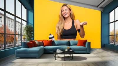 Young sport woman with a bottle of water over isolated background Wall mural