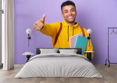 Young student Brazilian man isolated on purple background giving a thumbs up gesture Wall mural