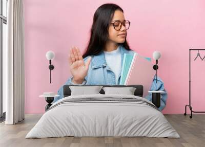 Young student Colombian woman isolated on pink background making stop gesture and disappointed Wall mural