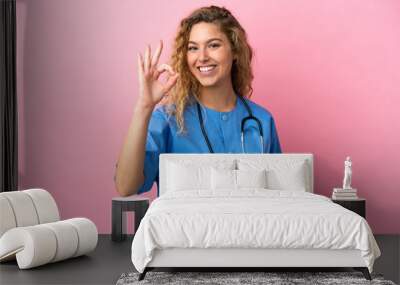 Young surgeon doctor woman isolated on pink background showing ok sign with fingers Wall mural