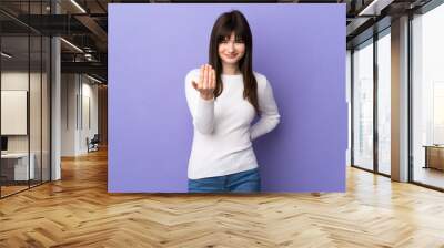 Young Ukrainian woman isolated on purple background inviting to come with hand. Happy that you came Wall mural