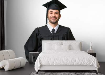 Young university graduate man over isolated background posing with arms at hip and smiling Wall mural