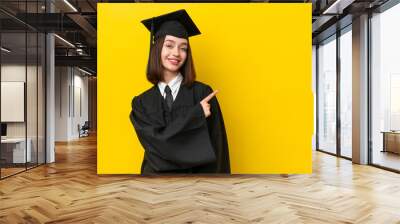 Young university graduate Ukrainian woman isolated on yellow background pointing to the side to present a product Wall mural