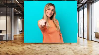 Young Uruguayan woman isolated on blue background pointing front with happy expression Wall mural