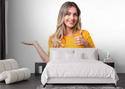 Young Uruguayan woman over isolated background holding copyspace imaginary on the palm to insert an ad and with thumbs up Wall mural