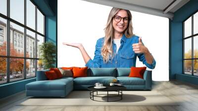 Young Uruguayan woman over isolated background holding copyspace imaginary on the palm to insert an ad and with thumbs up Wall mural