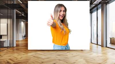 Young Uruguayan woman over isolated background with thumbs up because something good has happened Wall mural