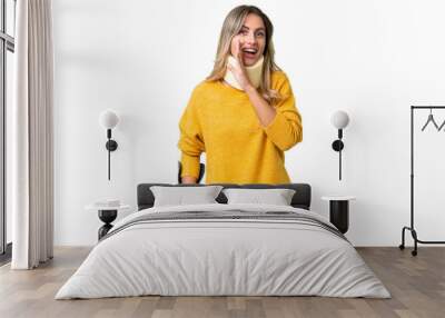 Young Uruguayan woman wearing neck brace and crutches over isolated background whispering something Wall mural