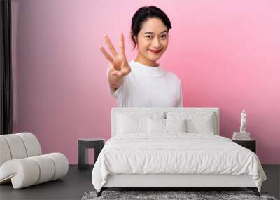 Young Vietnamese woman isolated on pink background happy and counting three with fingers Wall mural