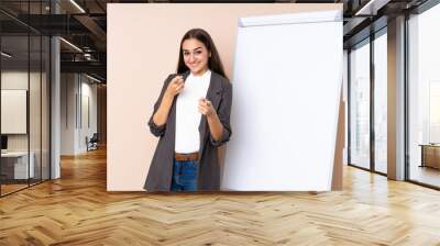 Young woman giving a presentation on white board points finger at you with a confident expression Wall mural