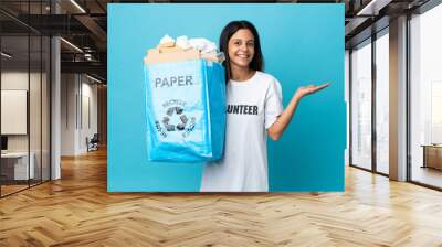 Young woman holding a recycling bag full of paper extending hands to the side for inviting to come Wall mural