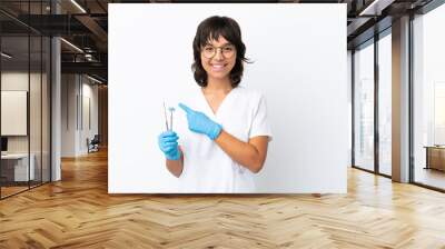 Young woman holding tools isolated on white background pointing to the side to present a product Wall mural