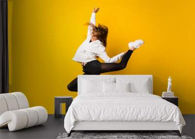 Young woman jumping over isolated yellow wall Wall mural