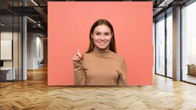 Young woman over colorful background pointing with the index finger a great idea Wall mural