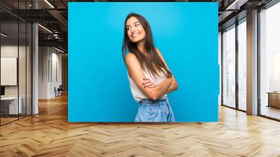 Young woman over isolated blue background Looking front Wall mural