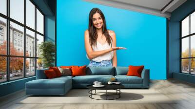 Young woman over isolated blue background smiling with a happy and pleasant expression Wall mural