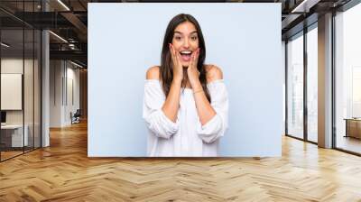 Young woman over isolated blue background with surprise facial expression Wall mural