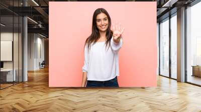 Young woman over isolated pink background happy and counting four with fingers Wall mural