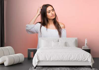 Young woman over isolated pink background having doubts while scratching head Wall mural