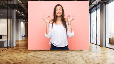 Young woman over isolated pink background in zen pose Wall mural