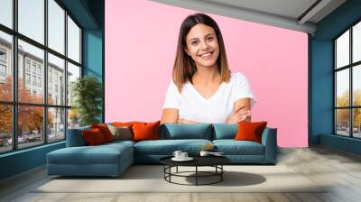 Young woman over isolated pink background keeping the arms crossed in frontal position Wall mural