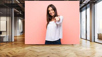 Young woman over isolated pink background points finger at you with a confident expression Wall mural