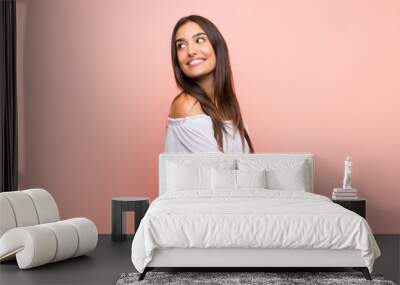 Young woman over isolated pink background with arms crossed and happy Wall mural