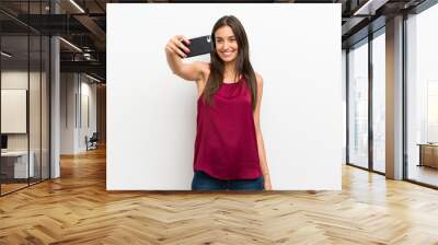 Young woman over isolated white background making selfie with cellphone Wall mural