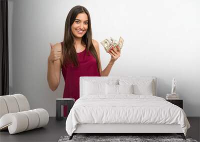 Young woman over isolated white background taking a lot of money Wall mural