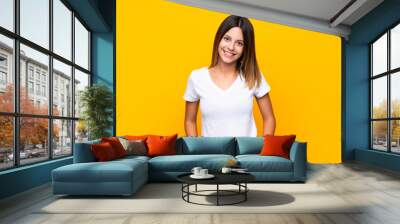 Young woman over isolated yellow background laughing Wall mural