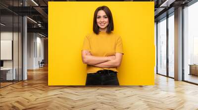 Young woman over yellow wall keeping the arms crossed in frontal position Wall mural