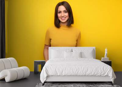 Young woman over yellow wall laughing looking to the front Wall mural