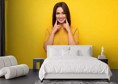 Young woman over yellow wall smiling with a happy and pleasant expression Wall mural