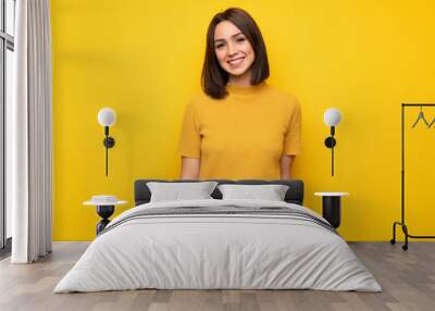 Young woman over yellow wall smiling Wall mural