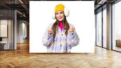 Young woman wearing winter muffs over isolated chroma key background making money gesture Wall mural