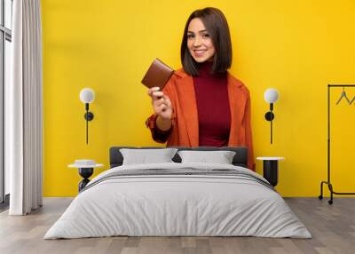 Young woman with coat holding a wallet Wall mural