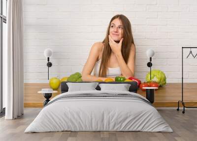 Young woman with many vegetables thinking an idea Wall mural