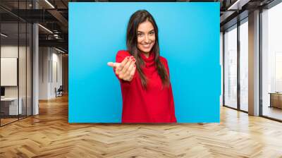 Young woman with red sweater over isolated blue background inviting to come Wall mural