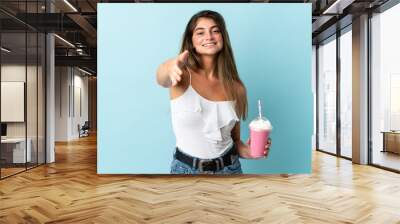 Young woman with strawberry milkshake isolated on blue background shaking hands for closing a good deal Wall mural