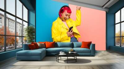 Young woman with yellow jacket celebrating a victory with a mobile Wall mural