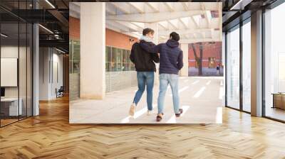 two college student boys walking hugging each other Wall mural