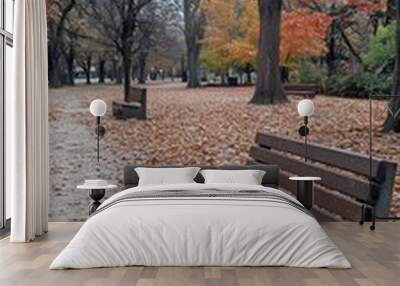 A photograph of two wooden benches placed on an autumn park path, surrounded by fallen leaves in shades of orange and brown Wall mural