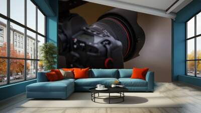 Close-up view of a camera on a tripod photographing a landscape with a medium lens attached. Wall mural